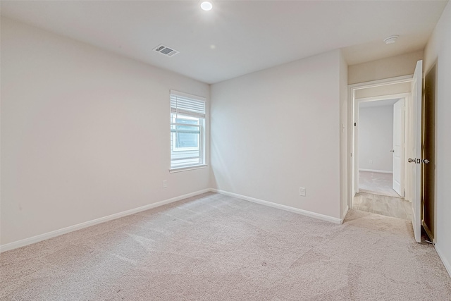 empty room with baseboards, visible vents, and light colored carpet