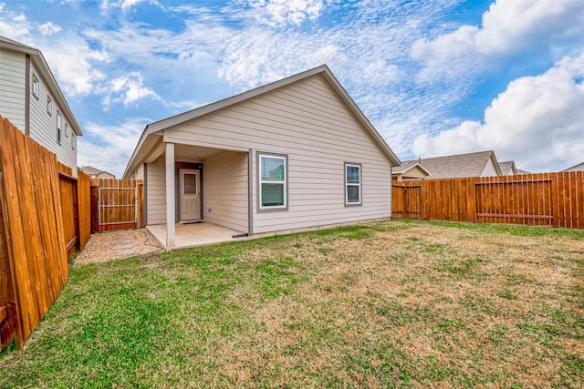 rear view of house with a yard, a patio, a fenced backyard, and a gate