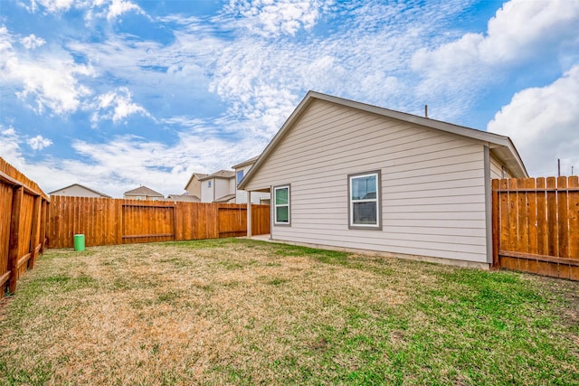 rear view of property featuring a fenced backyard and a lawn