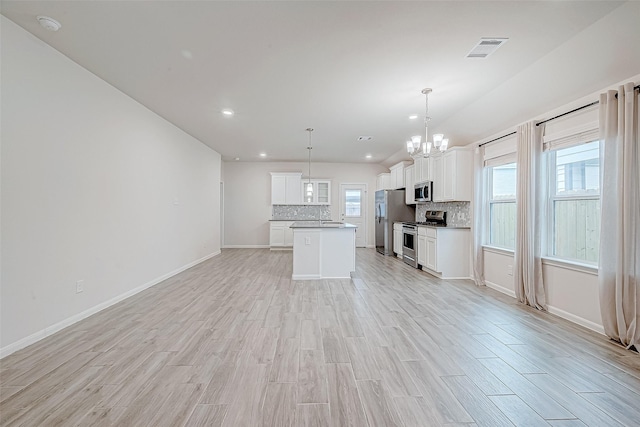 kitchen featuring visible vents, hanging light fixtures, appliances with stainless steel finishes, white cabinets, and a kitchen island