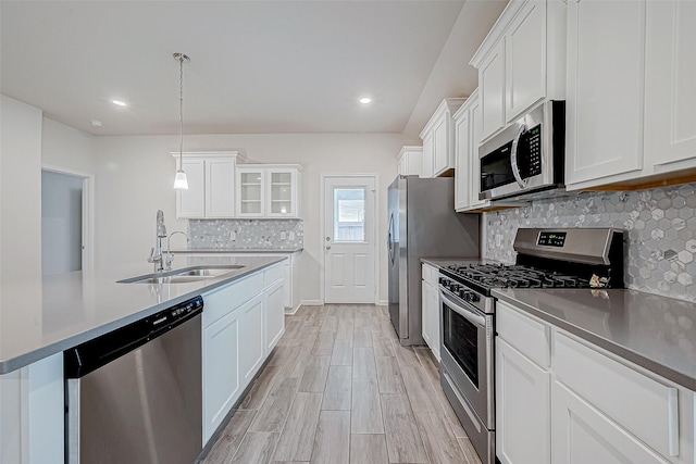 kitchen featuring white cabinets, glass insert cabinets, stainless steel appliances, and hanging light fixtures