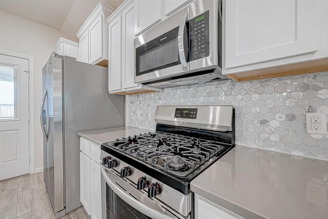 kitchen with white cabinetry, appliances with stainless steel finishes, decorative backsplash, light stone countertops, and light wood finished floors