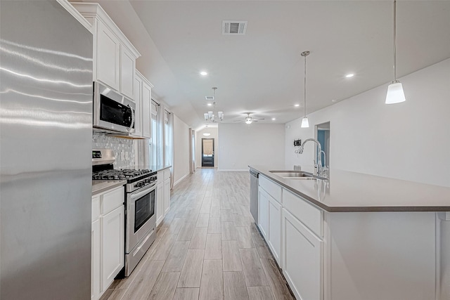 kitchen with visible vents, decorative light fixtures, a kitchen island with sink, stainless steel appliances, and a sink