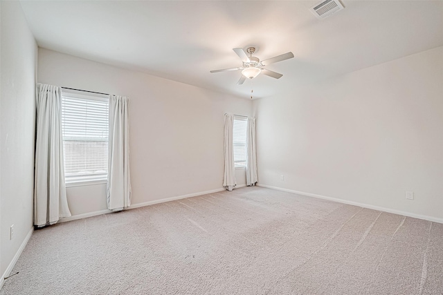 empty room with light colored carpet, a healthy amount of sunlight, visible vents, and baseboards