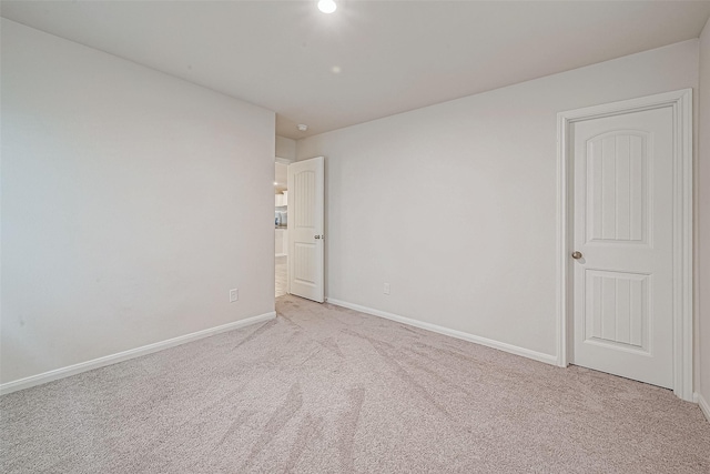 unfurnished room featuring baseboards and light colored carpet