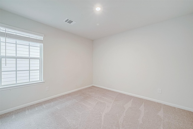 spare room featuring light carpet, baseboards, and visible vents