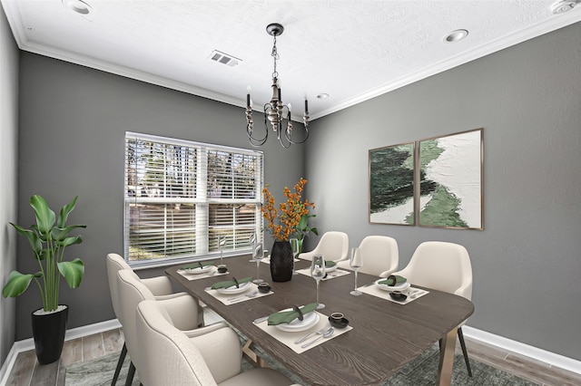 dining space with hardwood / wood-style floors, a notable chandelier, and ornamental molding