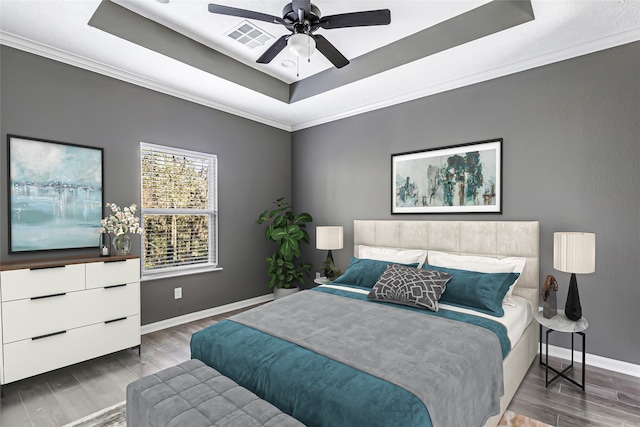 bedroom featuring dark hardwood / wood-style floors, a raised ceiling, ceiling fan, and ornamental molding