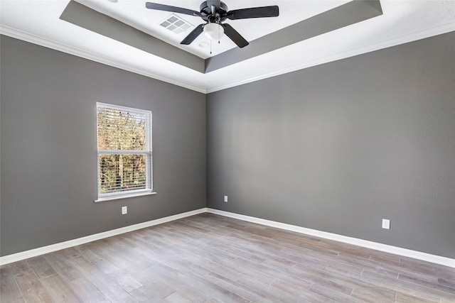 empty room featuring a raised ceiling, ceiling fan, light hardwood / wood-style flooring, and crown molding