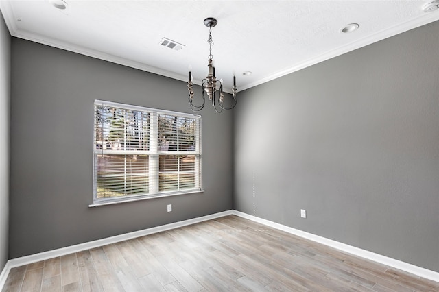 empty room featuring light hardwood / wood-style floors, ornamental molding, and an inviting chandelier