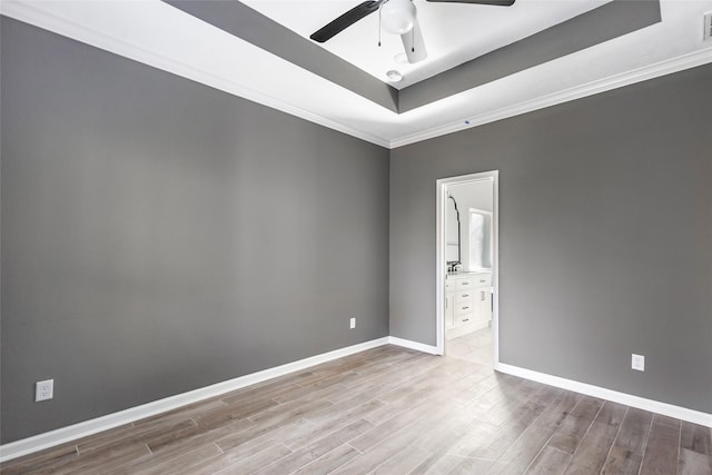 unfurnished room featuring ornamental molding, light hardwood / wood-style floors, ceiling fan, and a tray ceiling