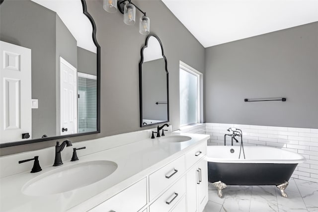 bathroom with a washtub, vanity, vaulted ceiling, and tile walls