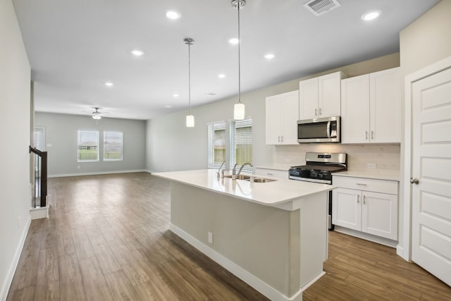 kitchen featuring stainless steel appliances, white cabinetry, sink, and a kitchen island with sink