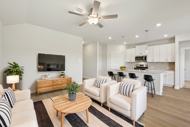 living area with lofted ceiling, recessed lighting, visible vents, light wood-style flooring, and ceiling fan