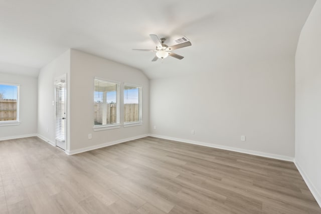 spare room featuring light wood-style flooring, baseboards, vaulted ceiling, and a ceiling fan