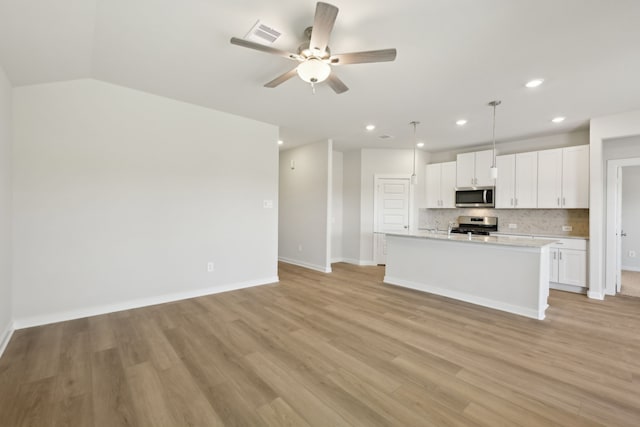 kitchen with open floor plan, decorative light fixtures, stainless steel appliances, light countertops, and white cabinetry