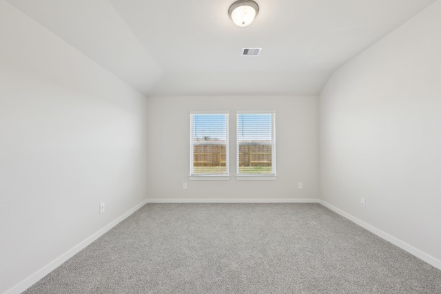 carpeted empty room featuring baseboards, visible vents, and vaulted ceiling