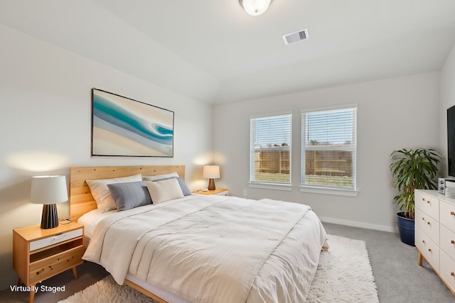 bedroom featuring baseboards, vaulted ceiling, visible vents, and light colored carpet