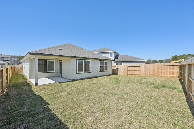 rear view of house with a patio, a shingled roof, a lawn, and a fenced backyard