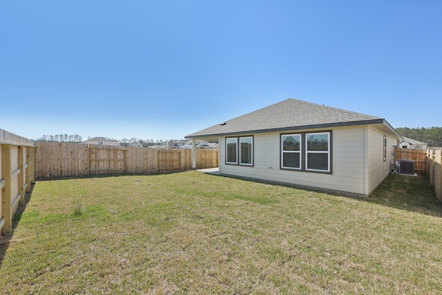 back of property with roof with shingles, central AC unit, a lawn, and a fenced backyard