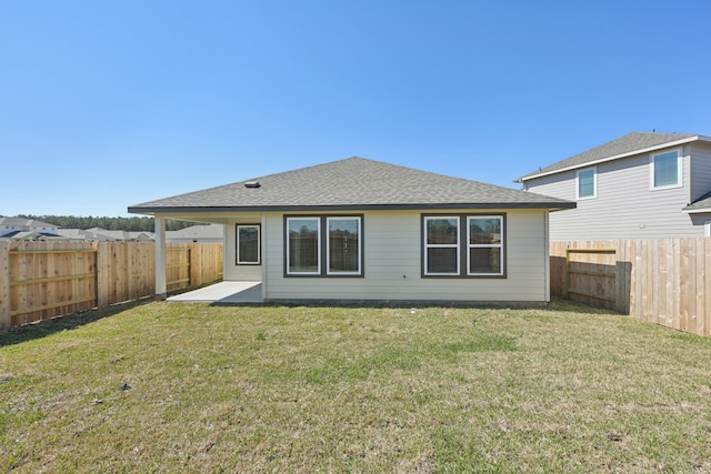 rear view of property with a shingled roof, a lawn, a patio area, and a fenced backyard