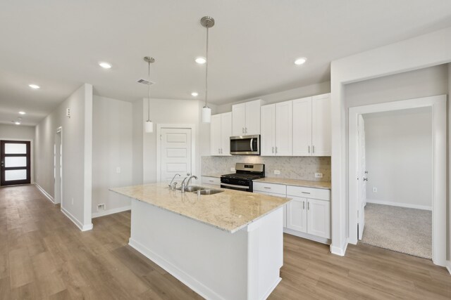 kitchen with stainless steel appliances, a kitchen island with sink, pendant lighting, and white cabinets