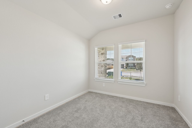 carpeted empty room with baseboards, visible vents, and vaulted ceiling