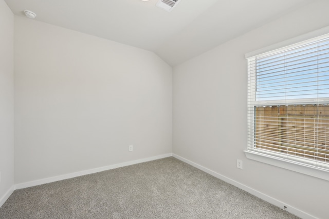 carpeted spare room with lofted ceiling, baseboards, and visible vents