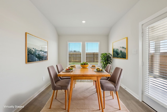 dining area with light wood-style floors, baseboards, and vaulted ceiling