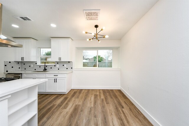 kitchen featuring sink, white cabinetry, tasteful backsplash, a notable chandelier, and hardwood / wood-style flooring