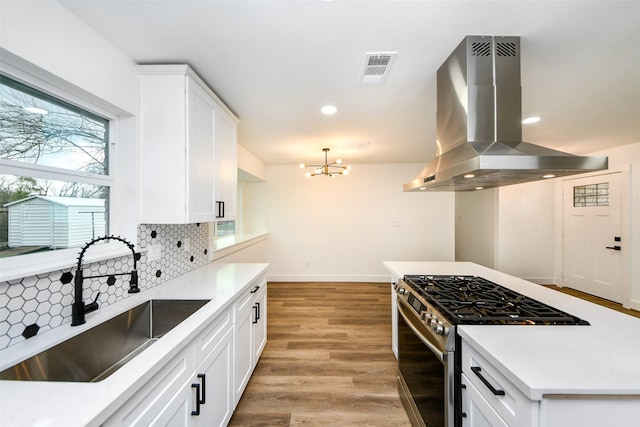 kitchen featuring sink, white cabinets, island exhaust hood, a notable chandelier, and gas stove