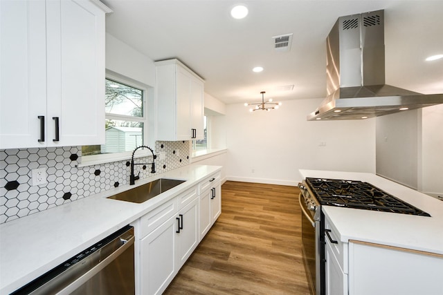 kitchen with island exhaust hood, appliances with stainless steel finishes, sink, and white cabinets