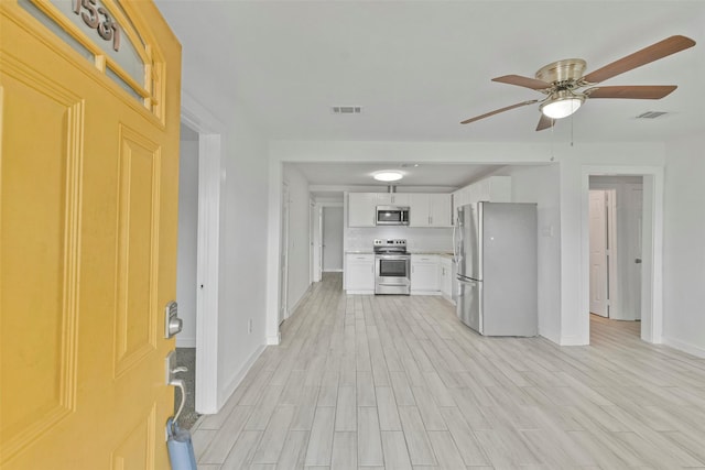 kitchen with white cabinets, stainless steel appliances, ceiling fan, and light hardwood / wood-style floors