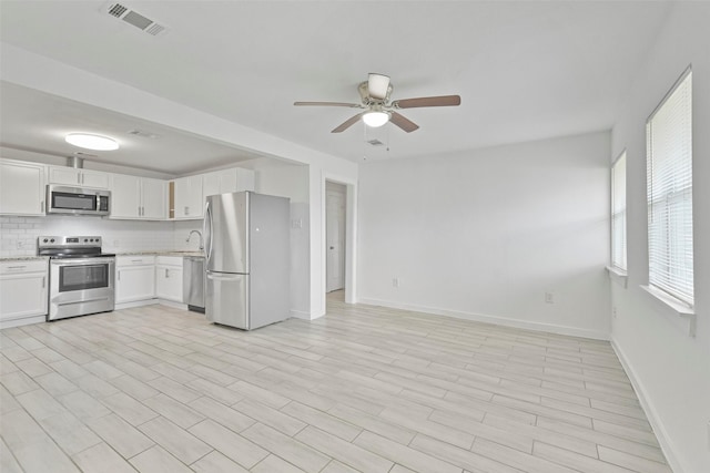 kitchen with white cabinetry, sink, ceiling fan, stainless steel appliances, and decorative backsplash