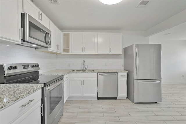 kitchen featuring white cabinets, light stone counters, sink, and stainless steel appliances