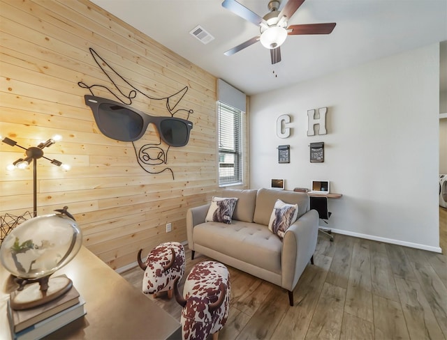 living room with hardwood / wood-style floors, ceiling fan, and wooden walls