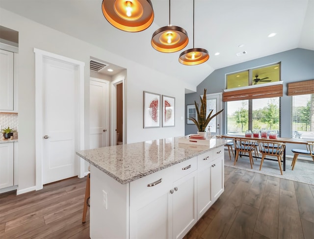 kitchen with a center island, lofted ceiling, dark wood-type flooring, decorative light fixtures, and white cabinetry