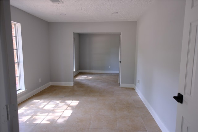 tiled spare room with a textured ceiling