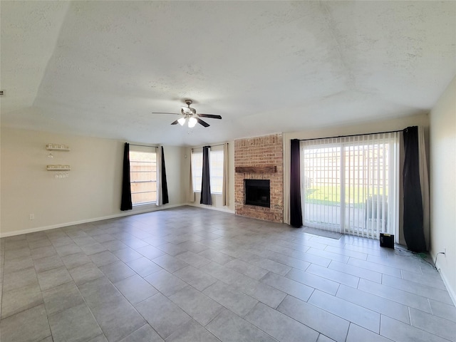 unfurnished living room featuring ceiling fan, a fireplace, light tile patterned floors, and a textured ceiling