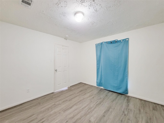 unfurnished room with a textured ceiling and light wood-type flooring