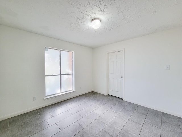 tiled empty room with a textured ceiling