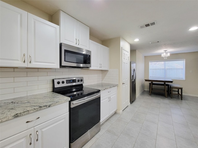 kitchen featuring light stone countertops, appliances with stainless steel finishes, backsplash, light tile patterned floors, and white cabinets