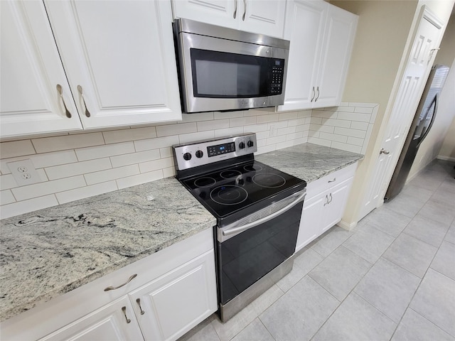 kitchen featuring light stone countertops, stainless steel appliances, light tile patterned floors, decorative backsplash, and white cabinets