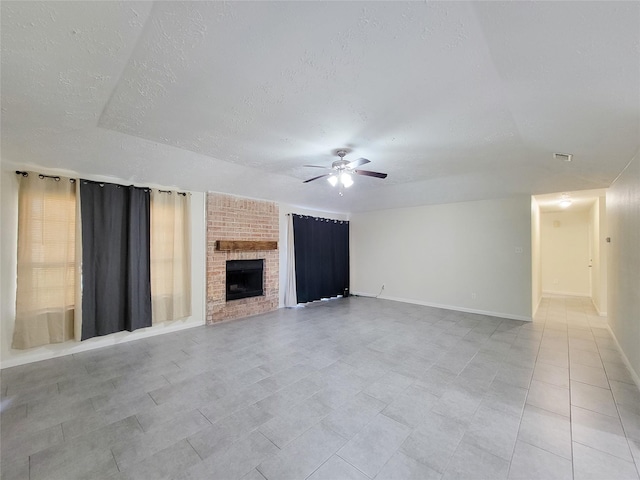 unfurnished living room featuring ceiling fan, a textured ceiling, and a brick fireplace