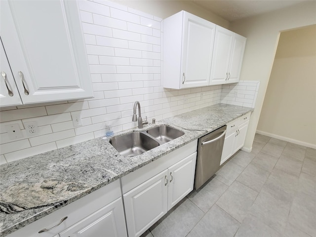 kitchen with sink, stainless steel dishwasher, light stone countertops, light tile patterned flooring, and white cabinetry