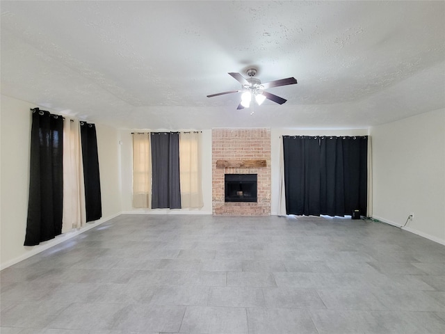 unfurnished living room with a textured ceiling, a brick fireplace, and ceiling fan