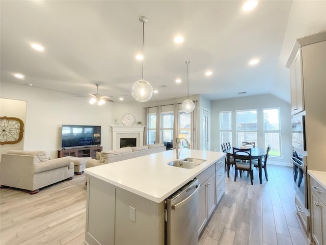 kitchen featuring sink, stainless steel appliances, an island with sink, decorative light fixtures, and white cabinets