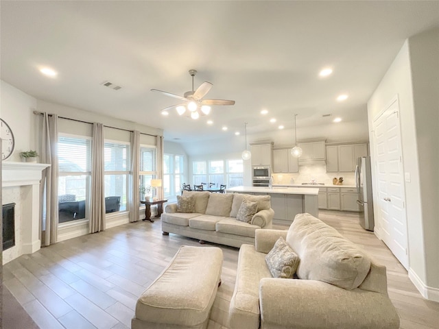 living room featuring ceiling fan, lofted ceiling, and light wood-type flooring