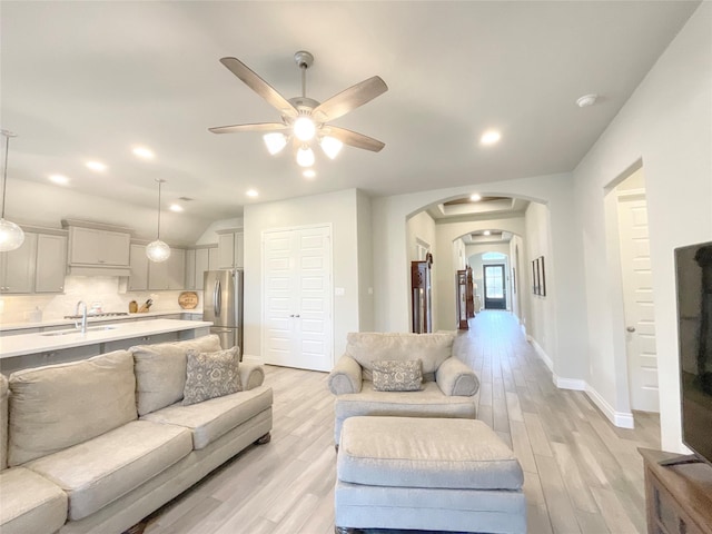 living room with ceiling fan, sink, and light wood-type flooring