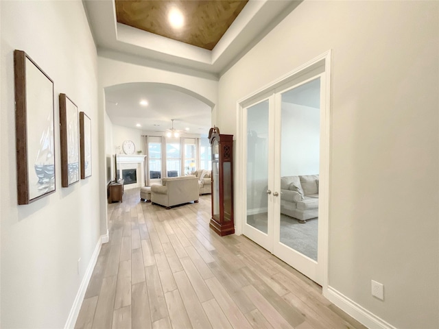 hallway featuring a raised ceiling, french doors, and light hardwood / wood-style floors